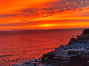 un tramonto sull'oceano con un edificio bianco di Casa Bianca A S'Angelo a Ischia