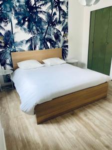- une chambre avec un grand lit et du papier peint tropical dans l'établissement Suite 24 Appart'hôtel-L'Annexe-3 étoiles, à Montceau-les-Mines