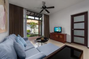 a living room with a blue couch and a television at Onyx Villas by TropicLook in Nai Harn Beach