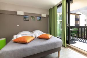 a bedroom with a bed with orange and white pillows at Belambra Clubs Seignosse - Les Tuquets in Seignosse