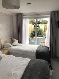 a bedroom with two beds and a window with a patio at Basingstoke En Suite Room in Garden Annex in Basingstoke