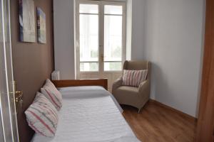- une chambre avec un lit, une chaise et une fenêtre dans l'établissement Albareda piso super-céntrico en Sarria, à Sarria