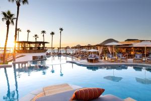 a large swimming pool with chairs and palm trees at ME Cabo by Meliá in Cabo San Lucas