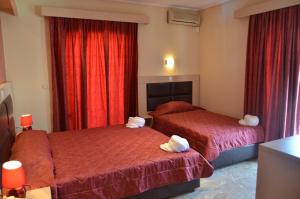 two beds in a hotel room with red curtains at Elli Maria in Limenas