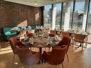 un comedor con mesas, sillas y ventanas en DOMITYS BASALTIK en Agde