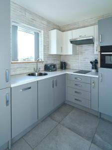 a kitchen with white cabinets and a sink and a window at Blue Watch in Lochaline