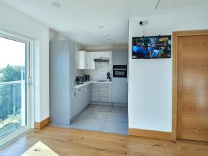a kitchen with white cabinets and a tv on the wall at Blue Watch in Lochaline
