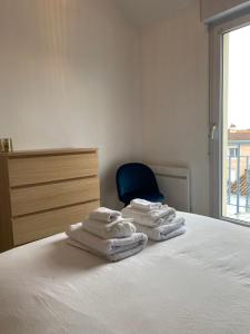 a group of towels sitting on a bed with a blue chair at Sacré cœur - Duplex avec balcon - 4 pers in Cholet