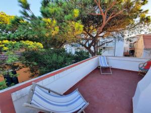 Zwei Stühle stehen auf einem Balkon mit einem Baum in der Unterkunft GetWet SurfCamp II in Costa da Caparica