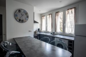 una cocina con mesa y sillas y un reloj en la pared en Le Saint Louis, en Périgueux