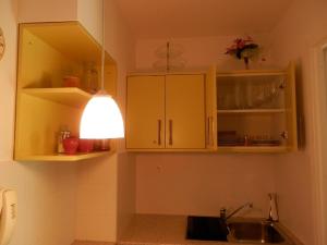 a kitchen with yellow cabinets and a light above a sink at Csiki Apartman in Budaörs