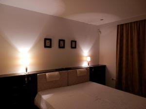 a bedroom with a bed with two lights on the wall at Csiki Apartman in Budaörs