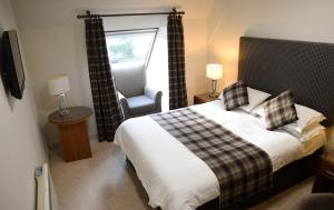 um quarto com uma cama, uma cadeira e uma janela em The Royal Hotel em Portree