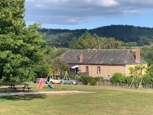 un parc avec une aire de jeux, un bâtiment et une maison dans l'établissement La Saucisserie Gites, à Saint-Pierre-de-Frugie