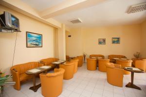 a waiting room with tables and chairs and a tv at Семеен Хотел Елена Палас in Nesebar