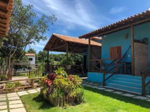 a blue house with a porch and some flowers at Pousada Luar de Caraíva in Caraíva