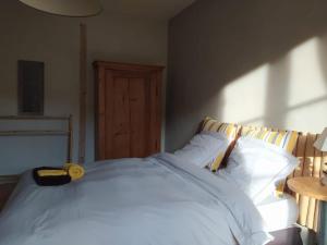1 dormitorio con 1 cama blanca grande y cabecero de madera en Les Amis de Gaure, en Rouffiac-dʼAude