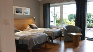 Pokój hotelowy z 2 łóżkami i krzesłem w obiekcie Lygnerns pensionat och konferens w mieście Sätila