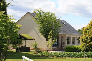 a small white house with a tree in the yard at Palmgrove Bed & Breakfast in Listowel