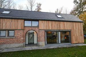 a brick house with a black roof and windows at L’annexe in Huy