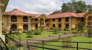 ein großes gelbes Gebäude mit einem grünen Hof in der Unterkunft Club del Campo - Hotel & Centro de Convenciones in Santo Domingo de los Colorados