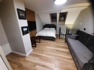 ein Wohnzimmer mit einer Couch und einem Bett in der Unterkunft Mieszkanie 2 pokojowe - 5km od SKI SUN Świeradów Zdrój in Pobiedna + 5 Fotos