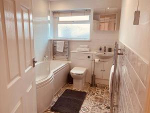a bathroom with a tub and a toilet and a sink at Comfy House with Parking for Multiple Vehicles in Cardiff