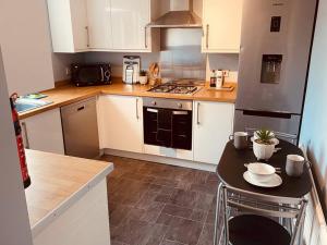 a kitchen with white cabinets and a black refrigerator at Comfy House with Parking for Multiple Vehicles in Cardiff