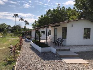 a white house with a patio and a table and chairs at Cabañas Campestres en Villavicencio in Villavicencio