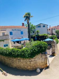 a stone wall with a palm tree in front of a building at B&B Nostromo in Funtana