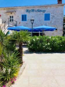 a patio with blue umbrellas in front of a building at B&B Nostromo in Funtana