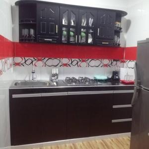 uma cozinha com armários pretos e um lavatório em Casa Hospedaje Sandra em Aguachica