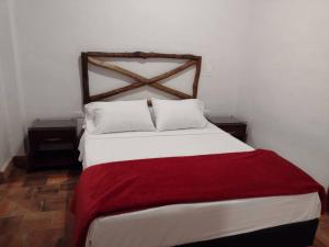 a bedroom with a large bed with a red blanket at Kazasha-Bari in Barichara