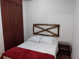 a bedroom with a white bed with a red blanket at Kazasha-Bari in Barichara