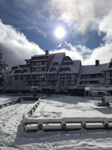 a building with snow on the ground in front of it at GALA Kop Apartman in Kopaonik