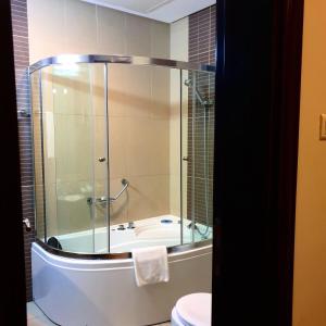 a bathroom with a shower and a tub and a toilet at Costa Del Sol Hotel by Arabian Link in Kuwait