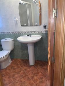 a bathroom with a sink and a toilet and a mirror at Apartamento El Campanario in Zuheros