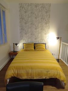 1 dormitorio con 1 cama grande con manta amarilla en Le Girond'Inn, en Libourne