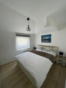 una camera da letto con un grande letto bianco e una finestra di Apartman Mateo Zlatar a Nova Varoš