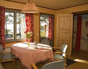 comedor con mesa, sillas y ventanas en Lummelunda Stugor, en Visby