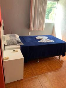 a small bedroom with a bed with a blue sheet at Pousada estância gaúcha in Guarapari