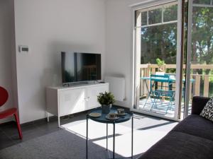 a living room with a couch and a tv and a table at Apt. neuf à 50m du port - Parking privé, ascenseur in Saint-Valery-sur-Somme