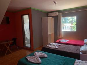 a hotel room with two beds and a window at Pousada estância gaúcha in Guarapari