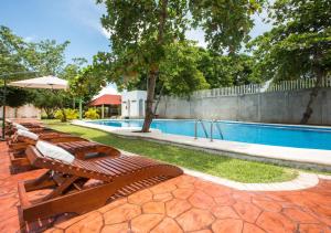 a group of wooden benches next to a swimming pool at KO'OLEBIL in Boca del cielo