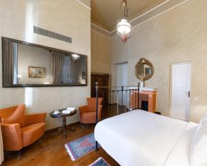 a bedroom with a bed and chairs and a mirror at Nafsimedon Hotel in Nafplio