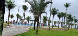 eine Gruppe von Palmen in einem Park mit Pool in der Unterkunft Vila Caiçara - Praia Grande in Praia Grande