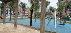 ein leerer Spielplatz mit Rutsche und Palmen in der Unterkunft Vila Caiçara - Praia Grande in Praia Grande