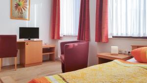 a hotel room with a bed and a desk with a television at Pension Haus Weierts in Norderney