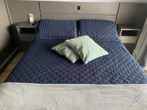 a bed with a blue comforter and a pillow on it at Flat Studio Charmoso New Studio Granja Viana Cotia in Cotia