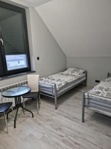 a room with two beds and a table and chairs at Noclegi 24/h Leszczynek in Kutno